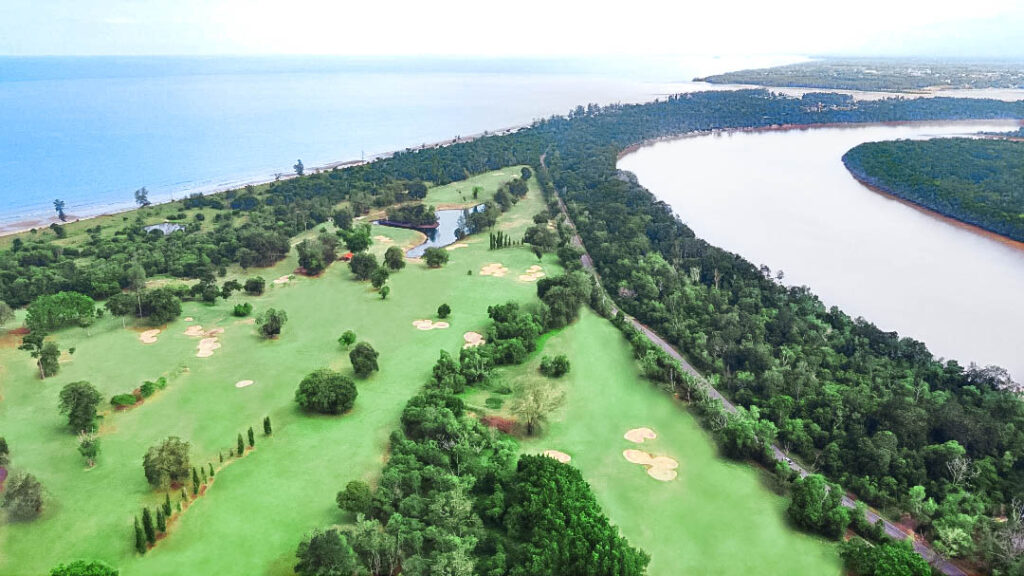 Bird's-eye view of a golf course surrounded with lush greenery next to the sea